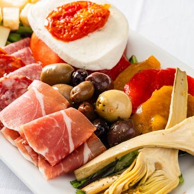 A plate of assorted cured meats, olives, cheese, and artichokes.
