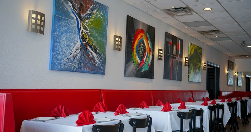 Interior, long banquette bench with red leather padding, tables and chairs, paintings on the wall