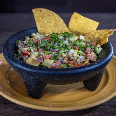Guacamole and tortilla chips served in a stone mortar.