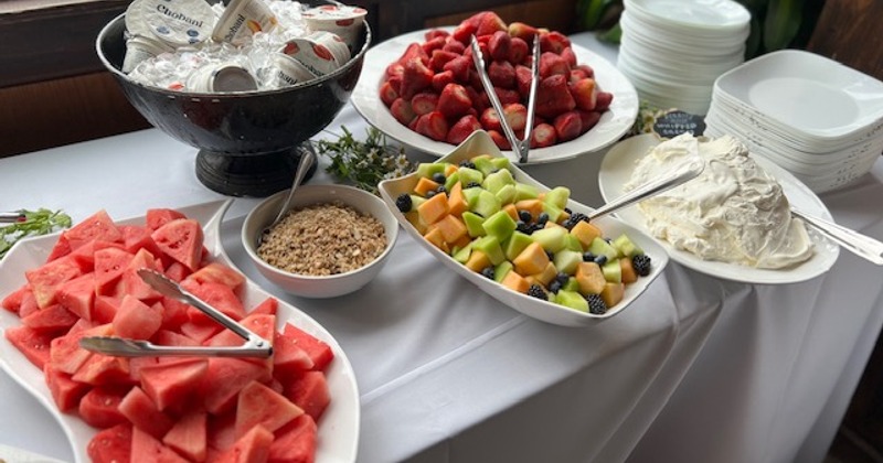 A buffet-style spread of various breakfast items such as fresh fruit, granola, yogurt, and cream