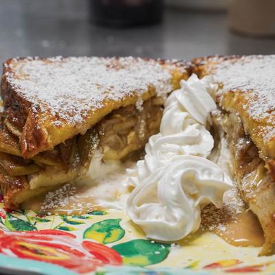 French toast with apple filling, topped with powdered sugar and whipped cream.