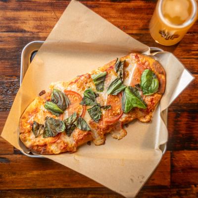 Flatbread topped with cheese, tomatoes and basil leaves.