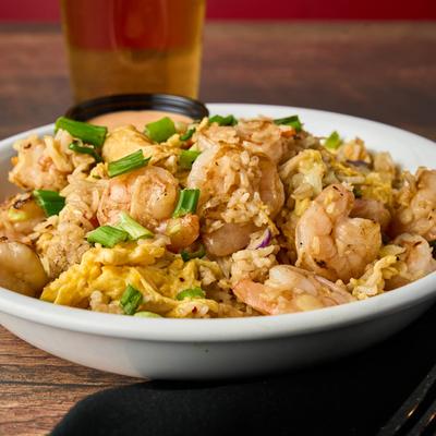 Shrimp fried rice with scallions and scrambled eggs, served with a beer.
