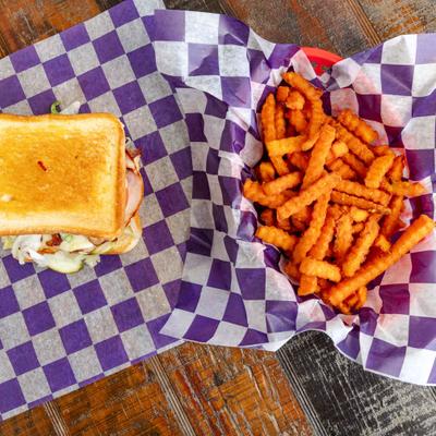 Grilled Club Sandwich served with sweet potato fries on the side.
