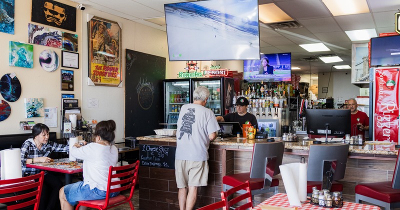 Dining area with a bar and tables with red and white tablecloths
