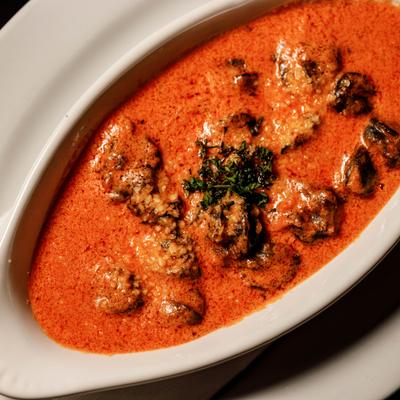 Escargot Alla Medici served in a creamy tomato-based sauce, topped with herbs.