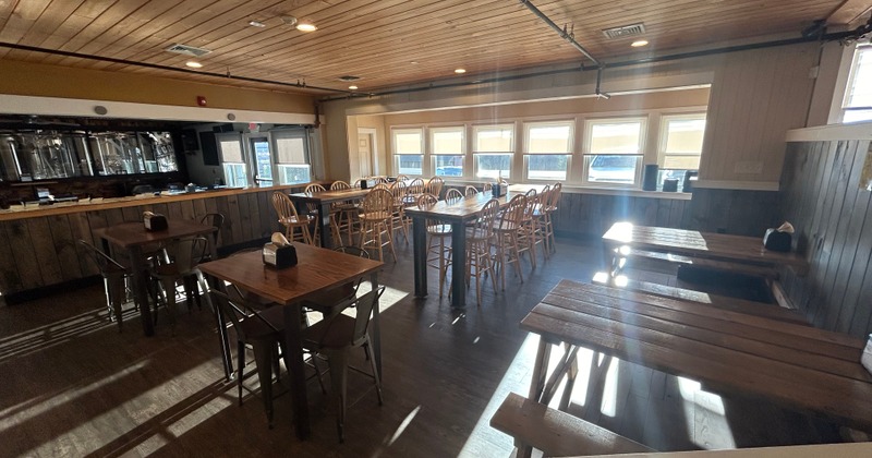 Bright dining area with wooden tables, chairs, and a bar