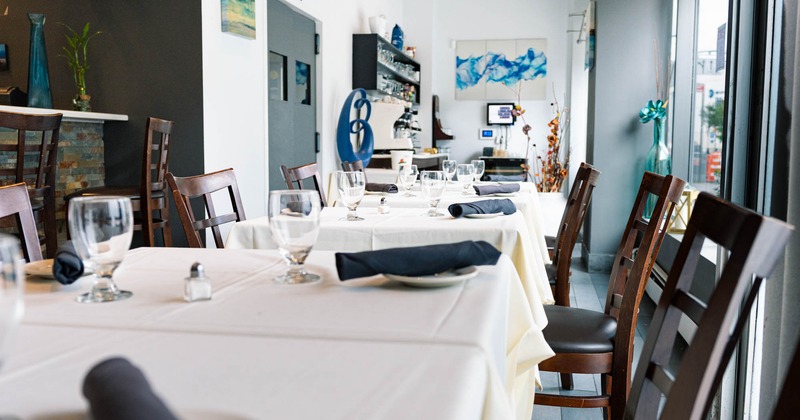 Interior, dining area, white cloth tables ready for guests, wooden chairs with padded seat