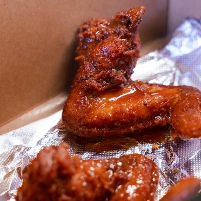 Hennessi wings served in a takeout box with foil lining.