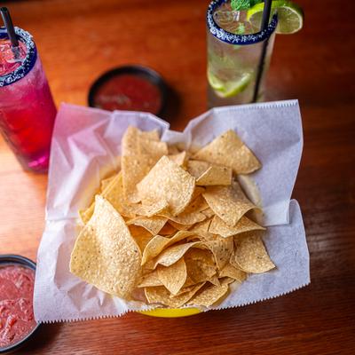 Tortilla chips, salsa, and cocktail drinks, top view.