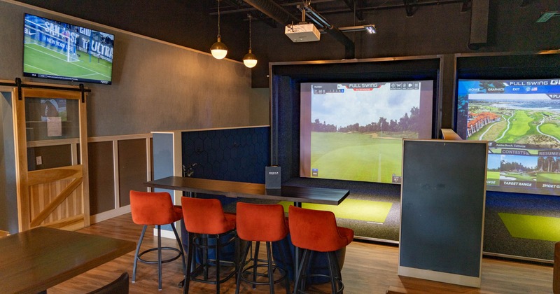 Interior, simulator room, high seating table with stools, large simulator screens