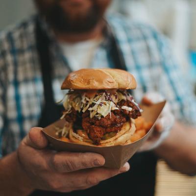 Chef holding a paper tray with Nashville Hot Chicken Sandwich.