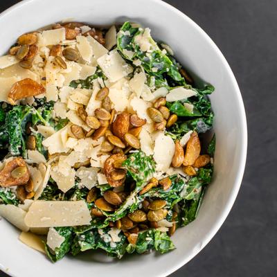 A kale salad with shaved parmesan, almonds, and pumpkin seeds.