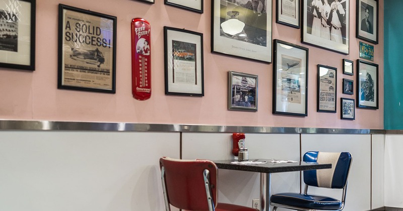 1950s-style restaurant interior, table for two, a wall decorated with pictures