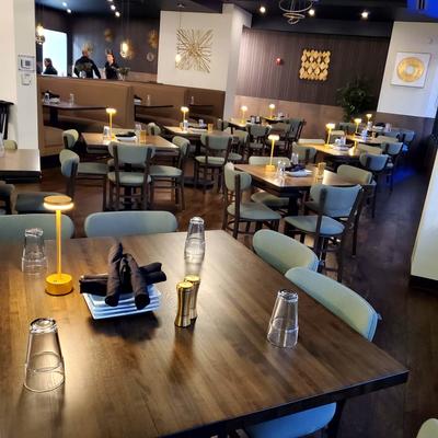 Interior dining room with wooden tables, chairs, and warm ambient lighting.