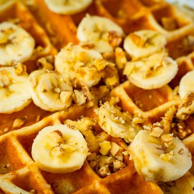 A close up of waffle with banana and nuts.