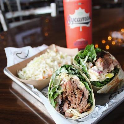 Brisket wrap served with coleslaw and a drink on a table
