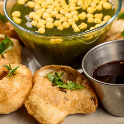 Puri shells served with pani flavored water and a sauce.