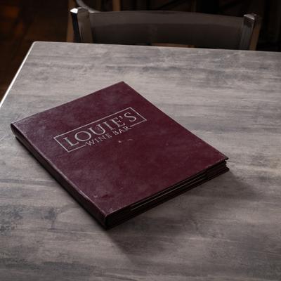Burgundy menu resting on a gray table.