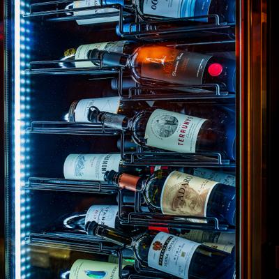 Wine bottles arranged inside a refrigerated display.