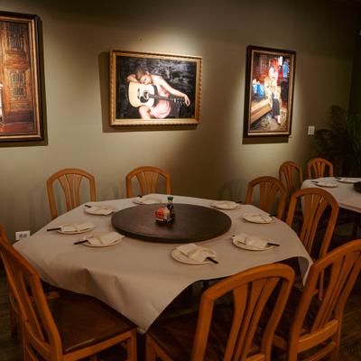 Restaurant interior with paintings on the wall and round dining tables below..