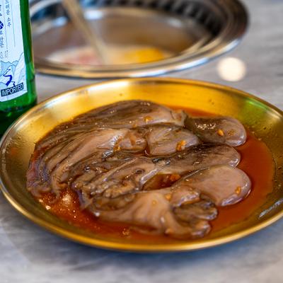 Raw octopus served on a brass-colored metal plate.