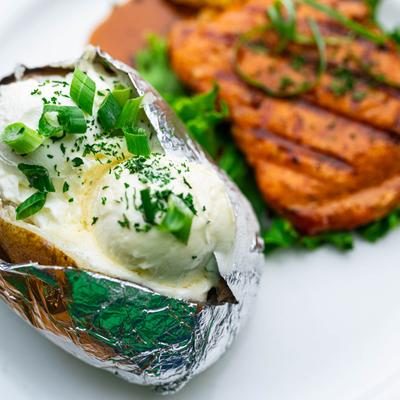 Bourbon glazed salmon served with a loaded baked potato, close up.