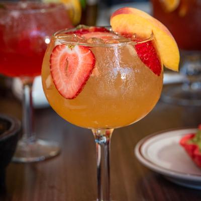 White Peach Margarita with strawberry slices and a peach slice.
