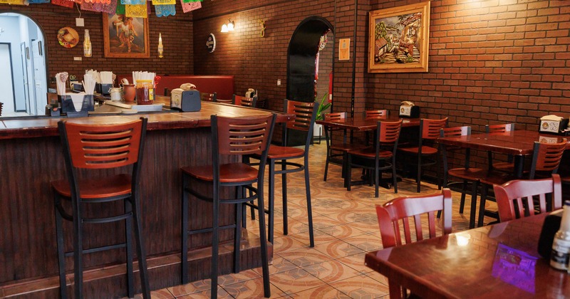Interior with bar, wooden tables and chairs and brick walls
