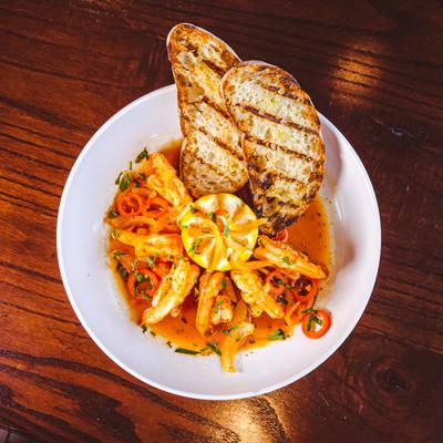 Shrimp, in sauce, with peppers, and toast.