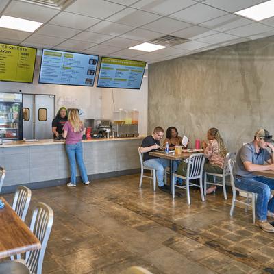 Interior, view of order counter and dining tables with seated guests.