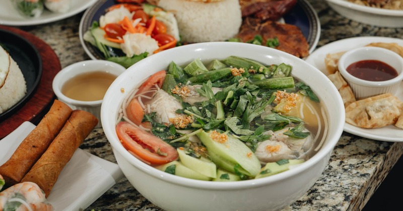 A bowl of Vietnamese noodle soup accompanied with Vietnamese broken rice dish