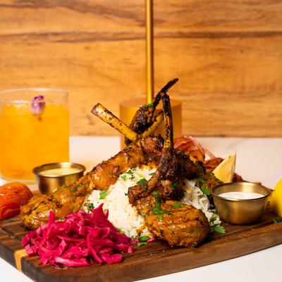 Lamb chops served over rice with pickled cabbage and sauces.