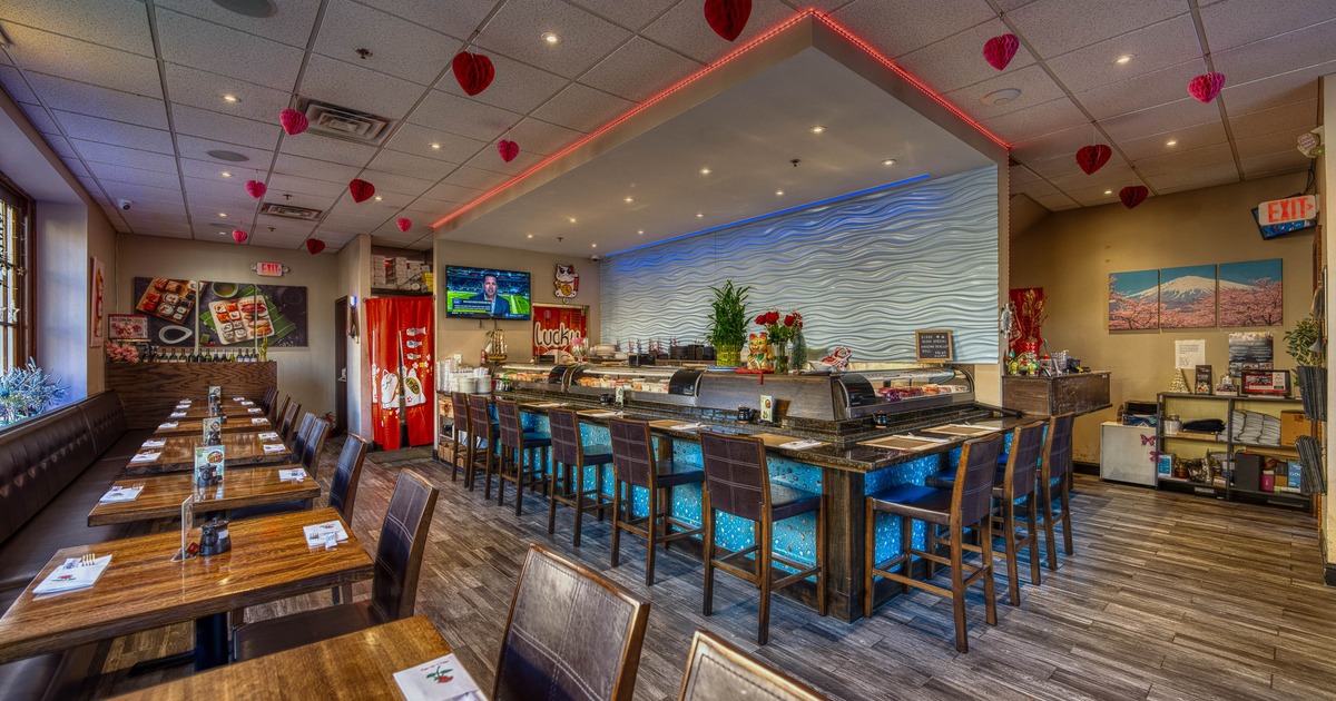 Cozy restaurant interior with wooden tables and chairs, a sushi bar with blue lighting