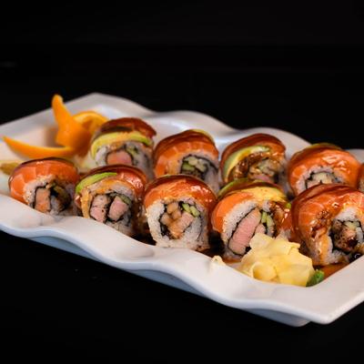Sushi rolls with tuna, salmon, avocado, and tobiko on a plate with pickled ginger.