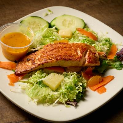 Grilled salmon with mixed greens, pineapple, tangerine, and dressing on the side.