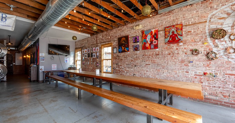 Interior, seating area, long wooden top tables and baches, red brick wall with decor