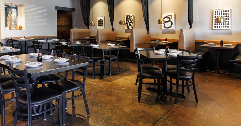 Interior - wooden tables, black chairs, cozy booths, pendant lighting and abstract artwork on walls