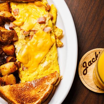 Ham and cheese omelet with buttered toast, home fries, and orange juice.