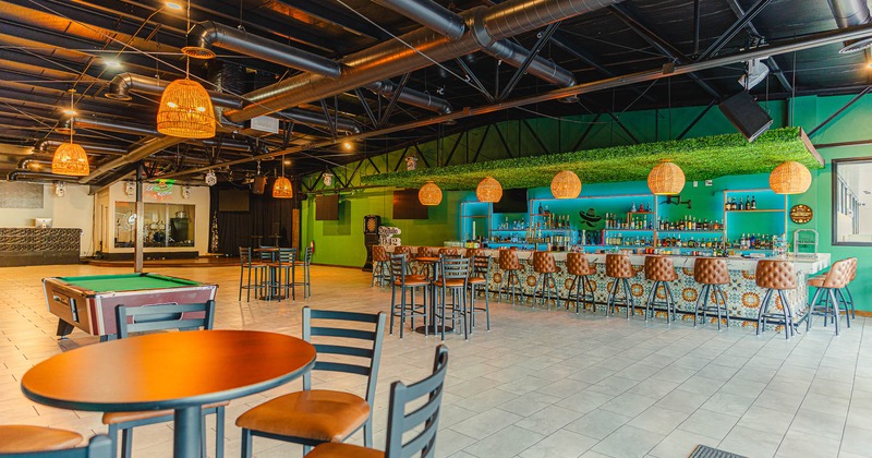 Interior, open area with bar, stools, tables and billiard pool table in the center