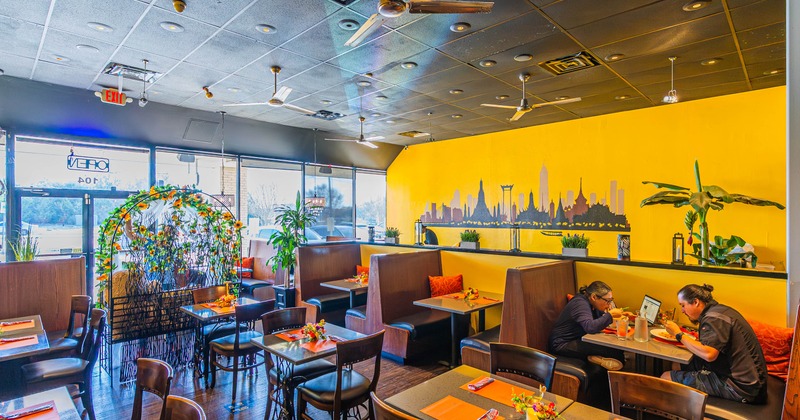 Dining room with both booth and table seating and a mural on the yellow wall