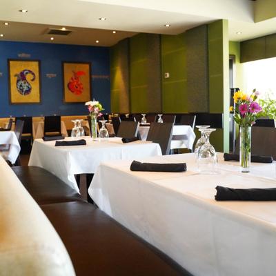 Interior, dining tables set with white tablecloths, black napkins, and vases of fresh flowers.