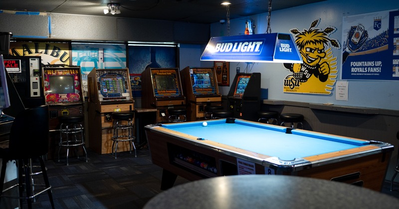 Billiard table, video game consoles in the background