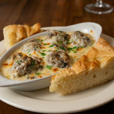 Baked beef meatballs in melted cheese sauce served with bread.