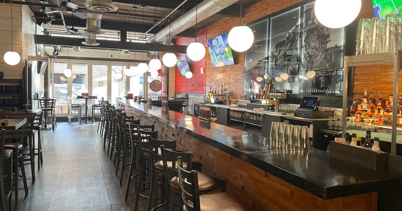 Bar area with a counter, high chairs and multiple TV screens