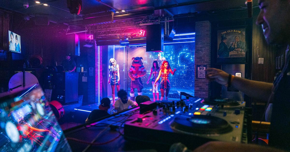 An event inside the pub with a DJ setup, a dance floor with performers, and vibrant lighting