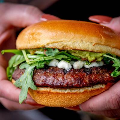 Burger with goat cheese, arugula, guacamole, and salsa.