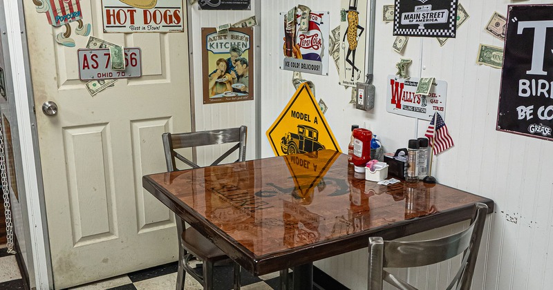 Table for two guests by the wall decorated with vintage signs and retro advertisements