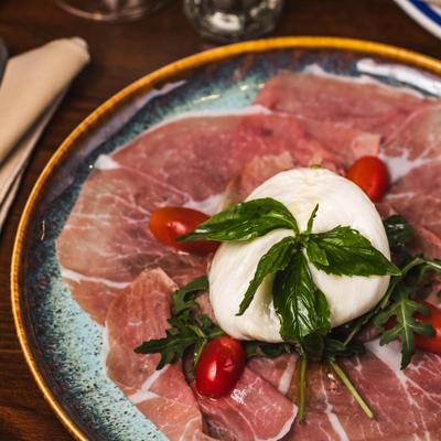 Prosciutto and burrata with basil and cherry tomatoes.