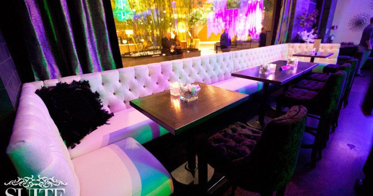 Interior, white button tufted banquette with  tables and dark upholstered chairs